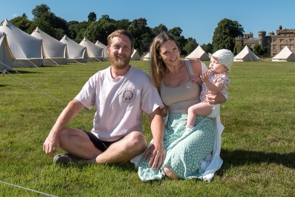 Ruby and Max, who run The Glamping Group, sitting in front of a row of bell tents